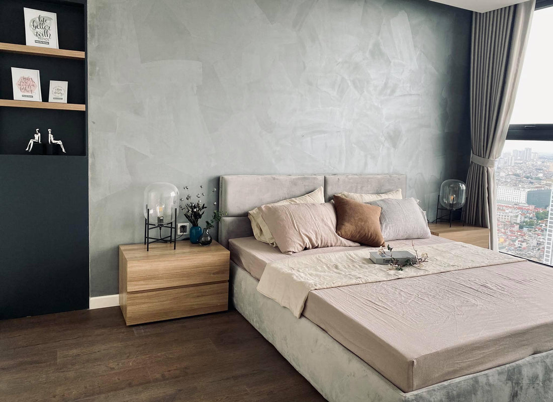 Stone beige SCANDALINEN French linen duvet cover on a high-rise apartment bed with concrete feature wall, city view and warm timber bedside table