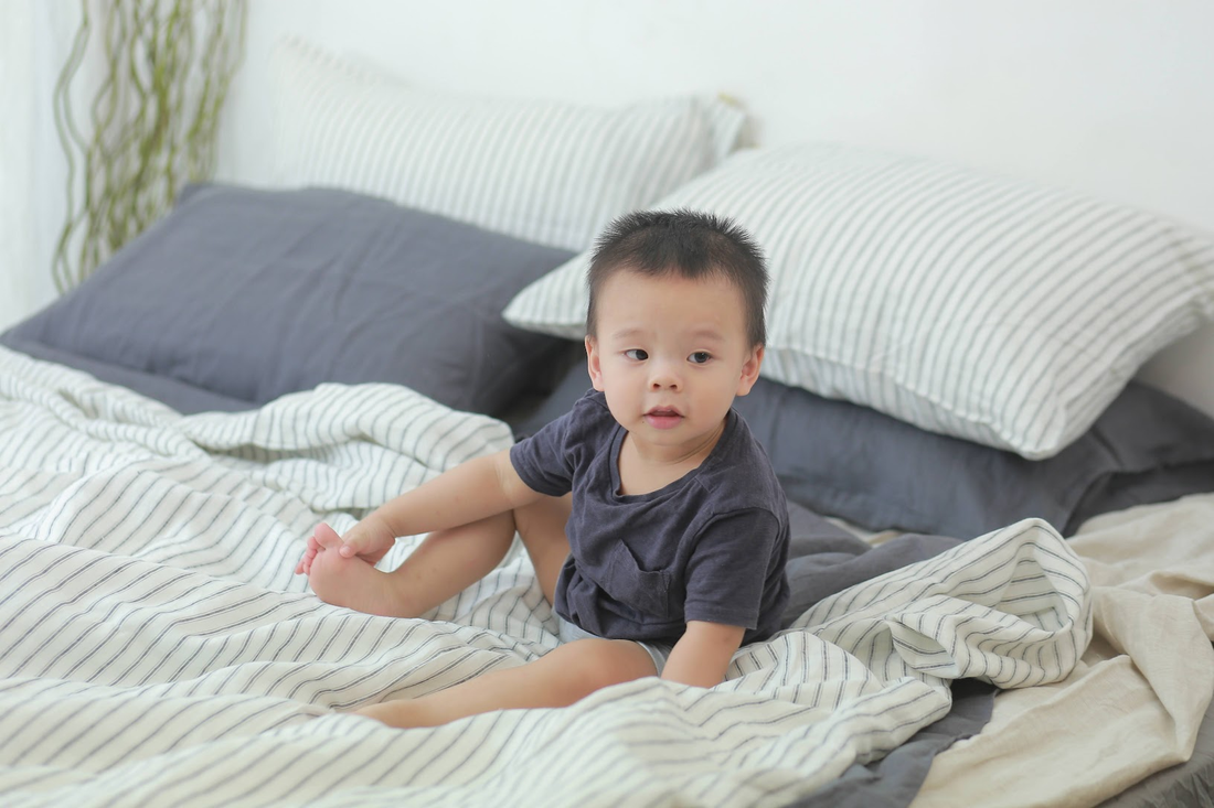 Baby sitting on French linen sheets — soft, hypoallergenic linen bedding safe for sensitive skin