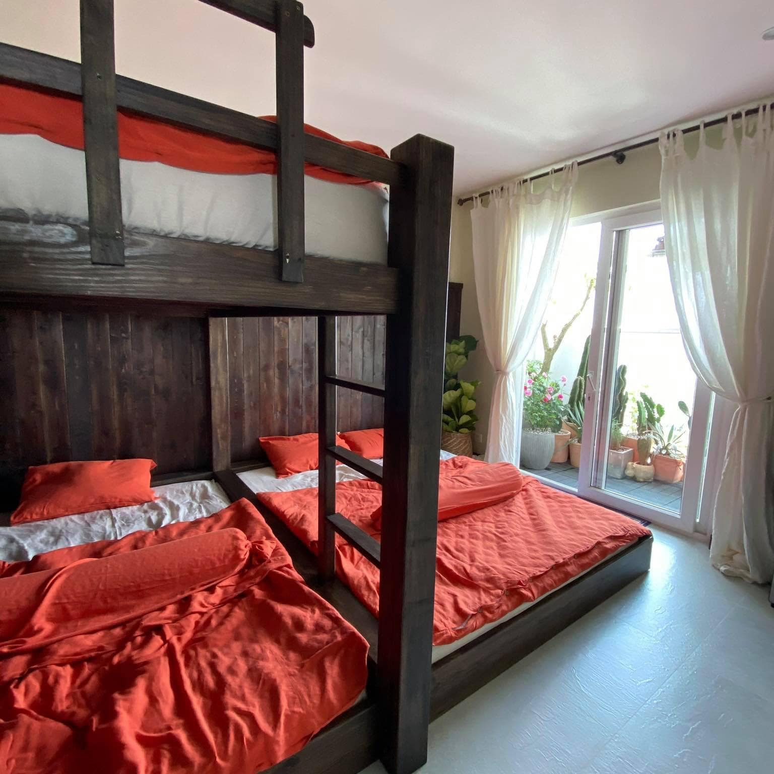 Rustic cabin bedroom with dark timber bunk beds and red-orange bamboo linen - SCANDALINEN