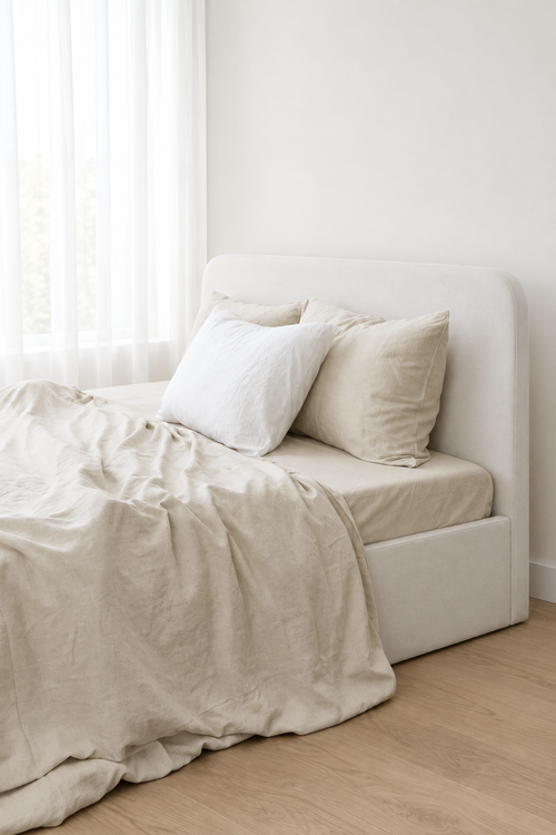 Angled view of beige bamboo linen duvet cover with soft folds and matching bedding in natural daylight