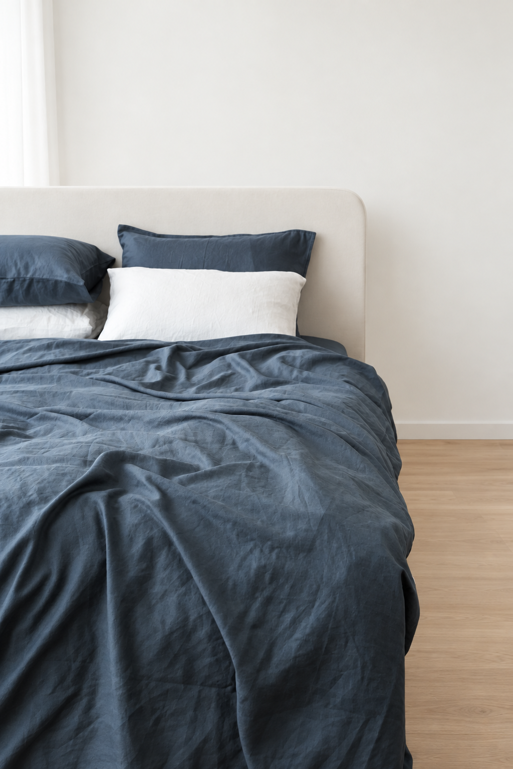 Grey bamboo linen duvet cover with natural folds, angled view against a bright ivory wall