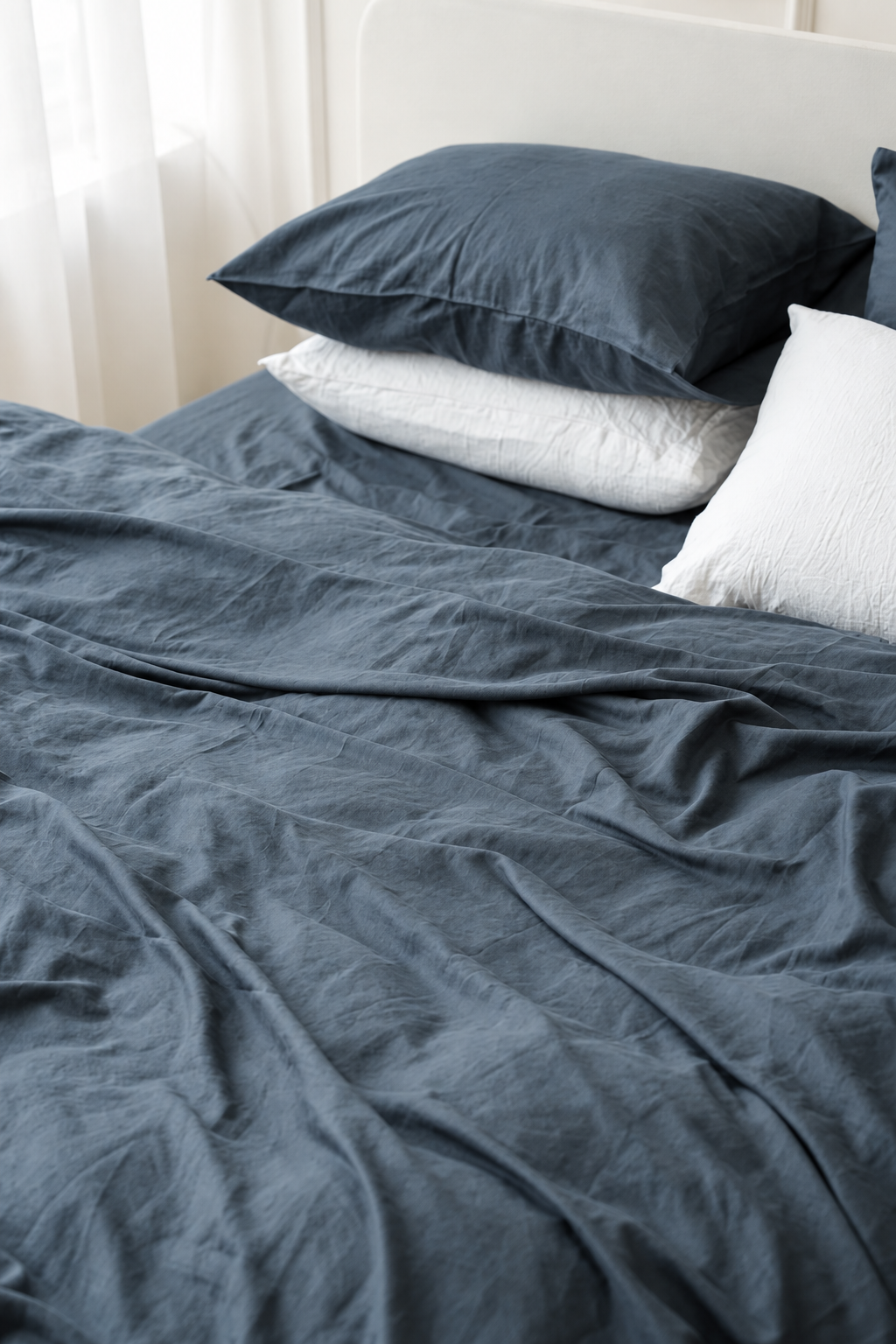 Slate grey bamboo linen pillowcase with visible woven texture, styled with white pillows in soft natural light