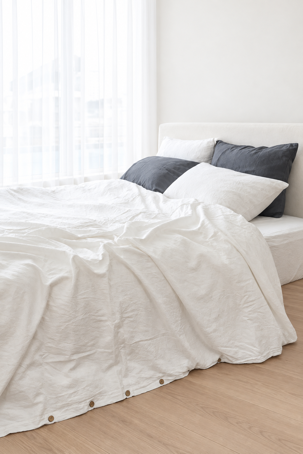 Angled view of a white bamboo linen duvet cover, showing natural folds and coconut shell buttons along the edge